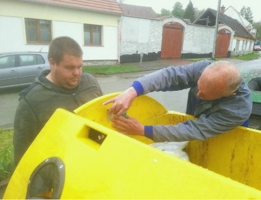Two man installing smart sensor into yellow container in the city of Ricany. 