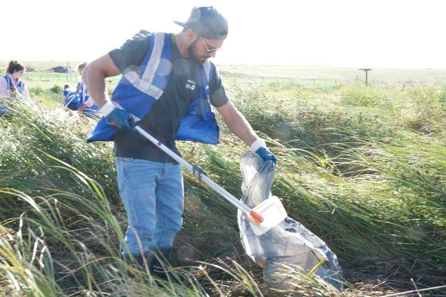 A man who is collecting trash at the countryside.