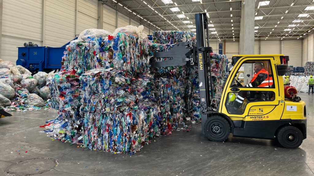 A worker in a forklift truck is moving recycled plastic bottles.