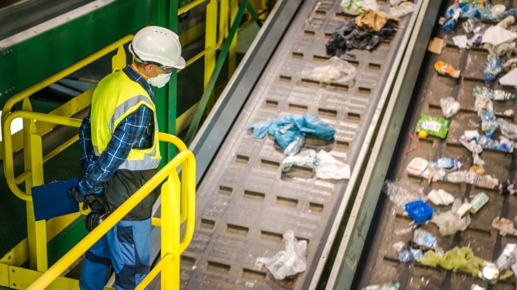 A worker is watching waste sorting in a sorting facility. 