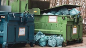 Large waste compactors and skips full of waste bags.