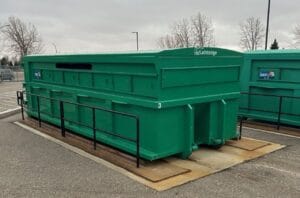 A large outdoor recycling or waste container secured on a concrete pad, designed for organized and efficient waste collection.
