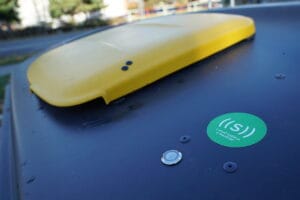 Yellow-lid recycling container with a small access-control sensor on the top surface.