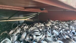 A container filled with numerous metal rings or components, viewed from inside the bin.