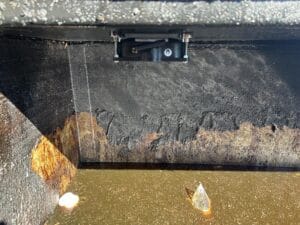 Rusty interior of a waste container with standing dirty water and a mounted sensor above.