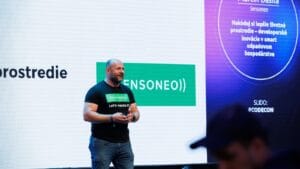  The Sensoneo CEO presents onstage with large Sensoneo graphics behind him.