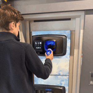 Person inserts a plastic bottle into a reverse-vending machine displaying recycling deposit information.