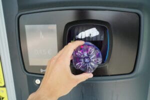 A person returns a plastic bottle into a deposit return machine to receive a refund.