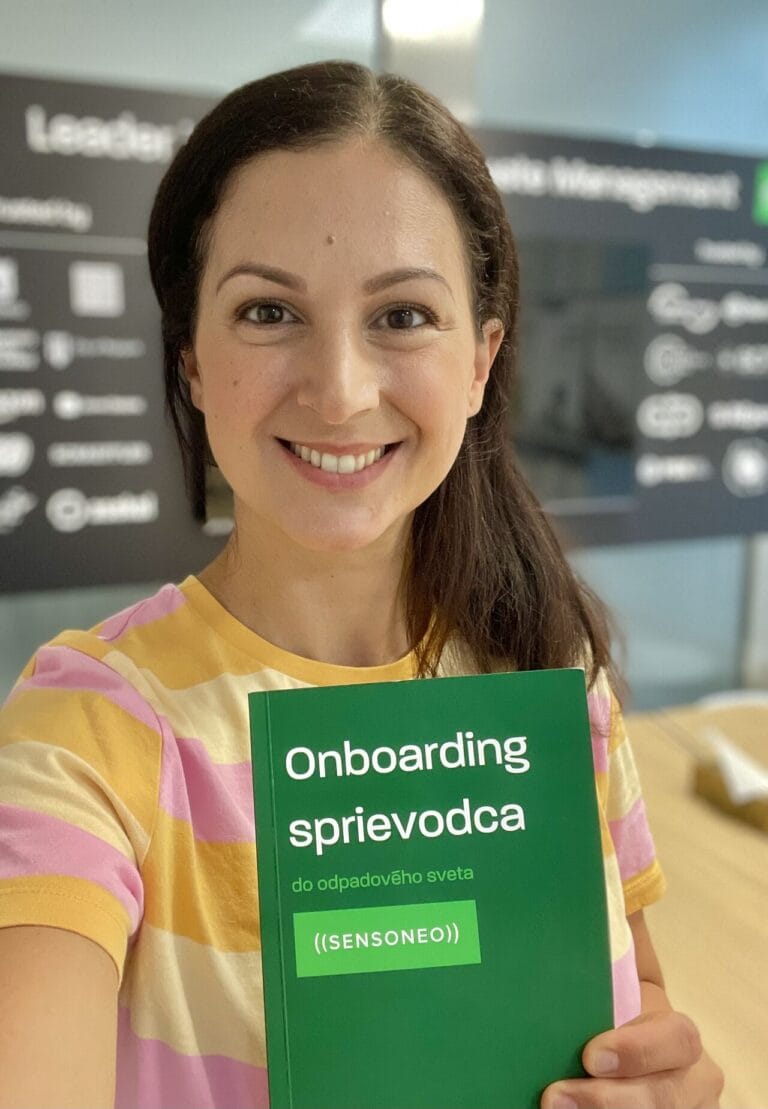 Office worker holding an onboarding guide booklet in an office setting.