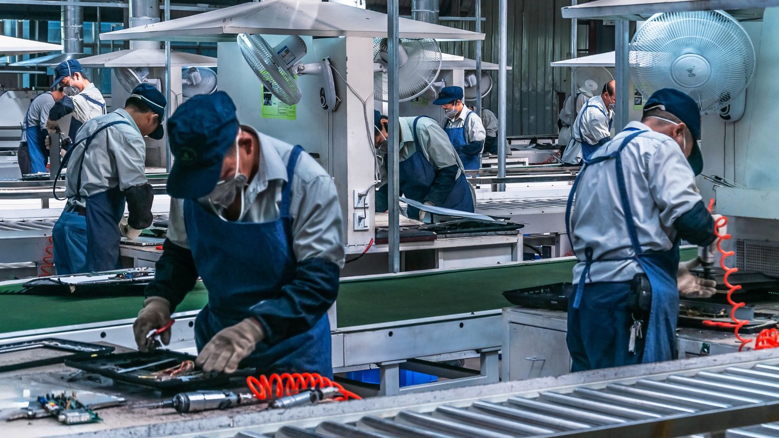 Workers assembling products on a busy industrial production line.