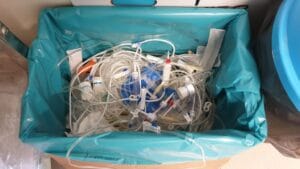 Container filled with used medical tubing and devices, highlighting biomedical waste segregation and disposal.