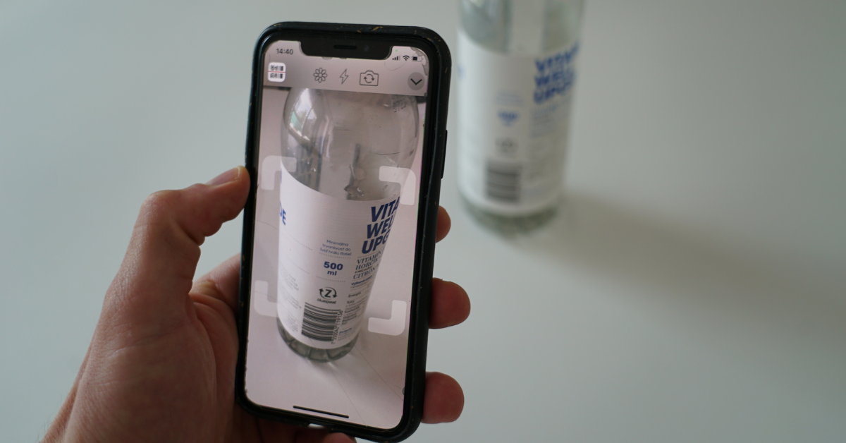 Person using a smartphone to scan a plastic bottle for recycling.