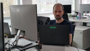A person working at a desk with two monitors in a modern office environment.
