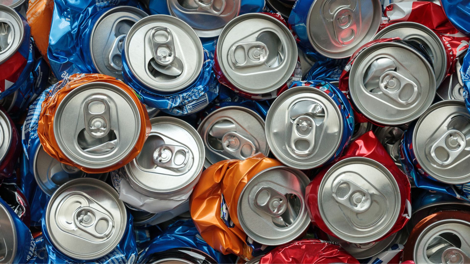 A pile of crumpled and unused aluminum cans in various colors.